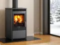 Poêle à bois Cadel en feu, avec une vue sur un paysage enneigé. L'alarme pressostat assure un fonctionnement sûr.