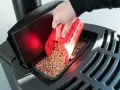 Main d'une personne versant des granulés de bois dans un poêle Palazzetti. Réglage de l'alimentation pour un fonctionnement optimal.