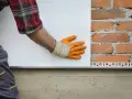 Pose d'isolant blanc sur mur de briques. Estimation du prix isolation extérieur maison 140m2.