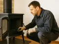 Un homme installe un poêle à granulés, vérifiant le tubage. Le coût de l'installation est une préoccupation pour de nombreux propriétaires.