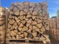 Un grand stère de bois, bien empilé et emballé sous plastique, prêt pour l'hiver.