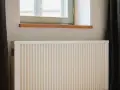 Radiateur électrique blanc sous une fenêtre, prêt pour un changement grâce à l'aide de l'état.