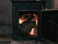 Poêle à bois avec porte ouverte et flammes vives dans le foyer.