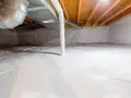 Vide sanitaire isolé avec une bâche blanche au sol et sur les murs, sous un plancher en bois avec des conduits.