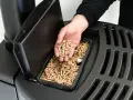 Main d'homme versant des granulés de bois dans un poêle, signalant une alarme manque pellet.