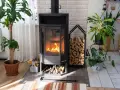 Poêle à bois allumé, entouré de plantes et de bois de chauffage. Une interdiction poêle à bois pourrait être envisagée pour des raisons de sécurité ou de pollution.