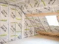 Pose d'un pare vapeur fibre de bois sur une structure métallique dans un grenier. Isolation en cours.