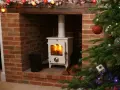 Installation d'un poêle à granulés avec conduit existant dans une cheminée en briques, décorée pour Noël.
