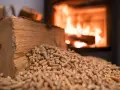 Bûches et granulés de bois, prêts pour une chaudière bois mixte. Le feu crépite en arrière-plan.