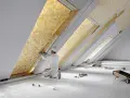 Un ouvrier installe un isolant thermique jaune texturé dans un grenier.
