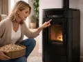Femme vérifiant l'alarme température fumée sur son poêle à granulés. Elle tient un panier de pellets.