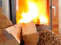 Bûches et granulés de bois près d'un poêle à granules en feu. Chaleur réconfortante pour l'hiver.