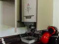 Chaudière gaz instantané De Dietrich installée dans un placard, à côté d'une machine à café rouge.