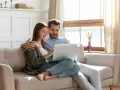 Couple planifiant l'amélioration de leur habitat, consultant un prêt sur leur ordinateur.