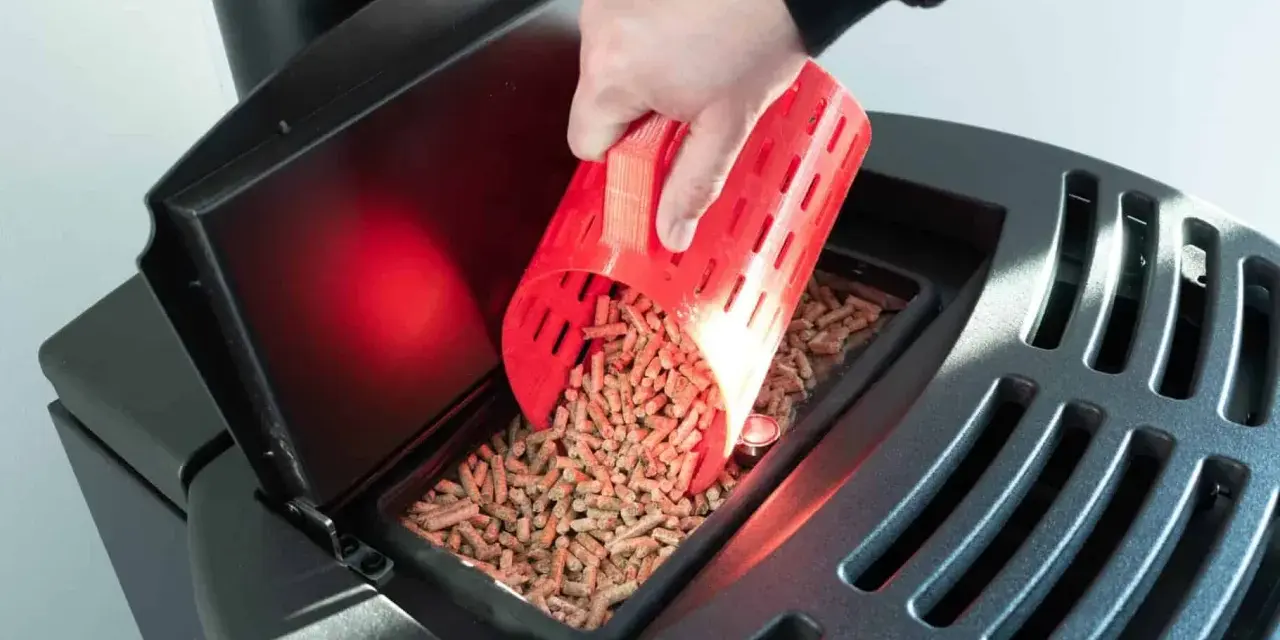 Main d'une personne versant des granulés de bois dans un poêle Palazzetti. Réglage de l'alimentation pour un fonctionnement optimal.