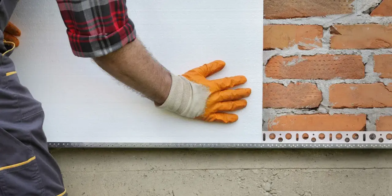 Pose d'isolant blanc sur mur de briques. Estimation du prix isolation extérieur maison 140m2.