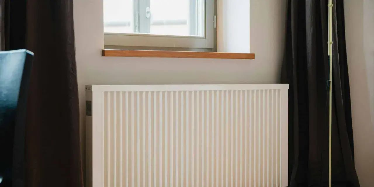 Radiateur électrique blanc sous une fenêtre, prêt pour un changement grâce à l'aide de l'état.