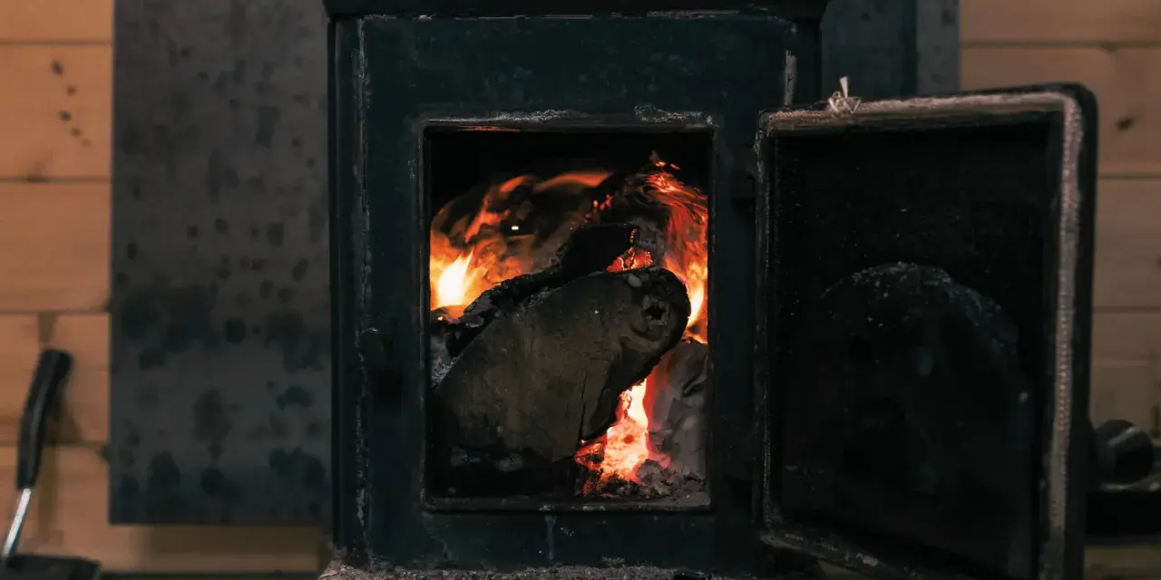 Poêle à bois avec porte ouverte et flammes vives dans le foyer.