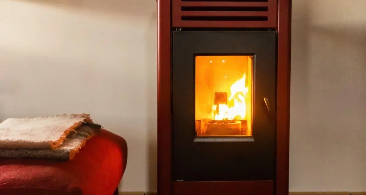 Poêle à bois avec soufflerie, ses flammes dansent joyeusement, réchauffant la pièce. Une couverture douillette est posée sur un fauteuil rouge à proximité.