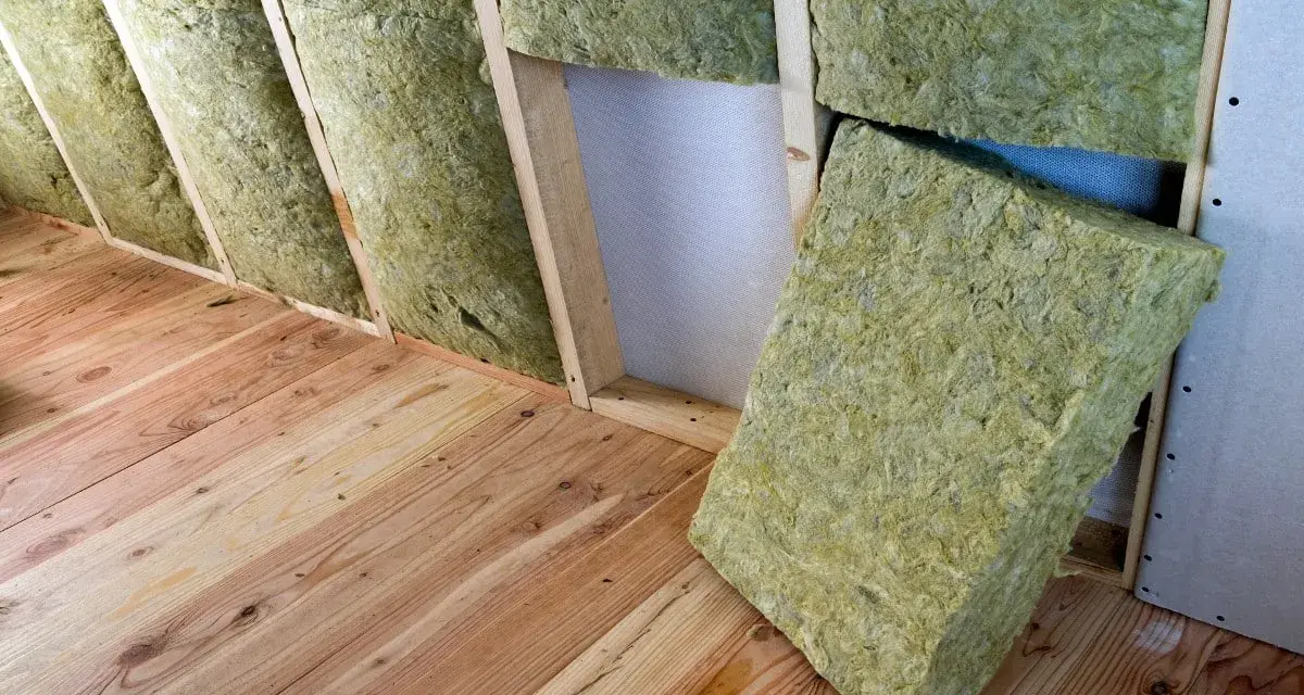 Isolation d'un grenier avec de la laine de verre sans pare vapeur, posée entre les chevrons sur un plancher en bois.