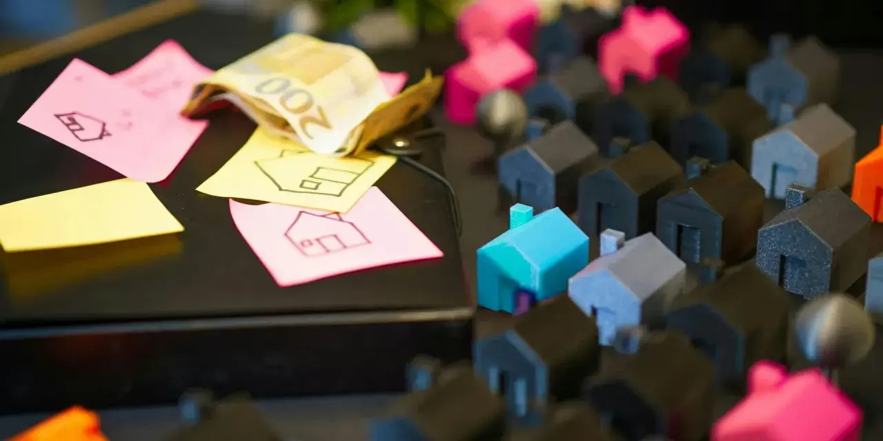 Petites maisons miniatures, billets de banque et post-its avec des dessins de maisons.