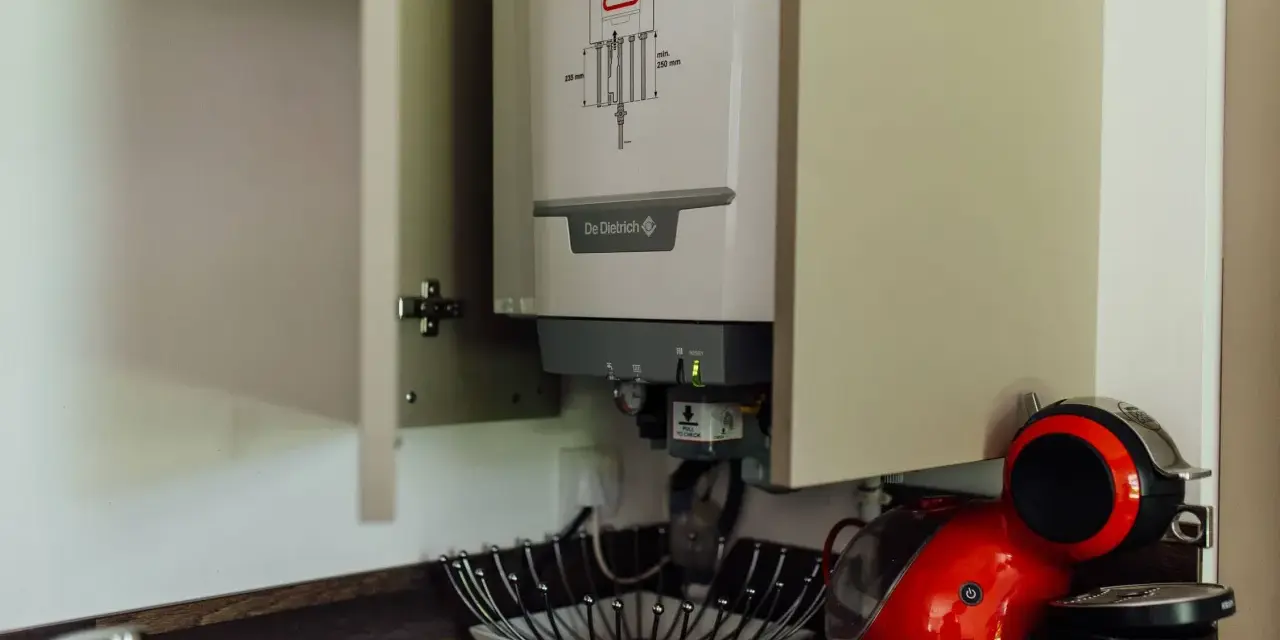 Chaudière gaz instantané De Dietrich installée dans un placard, à côté d'une machine à café rouge.