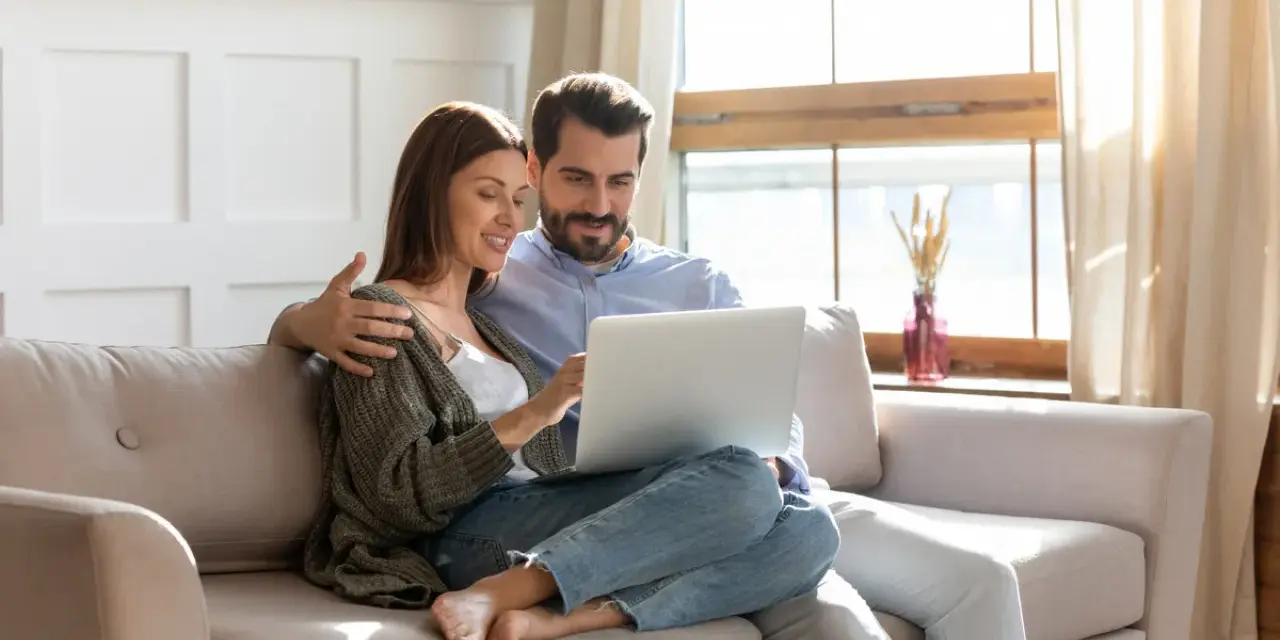 Couple planifiant l'amélioration de leur habitat, consultant un prêt sur leur ordinateur.