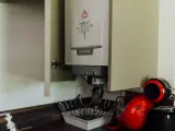Chaudière gaz instantané De Dietrich installée dans un placard, à côté d'une machine à café rouge.
