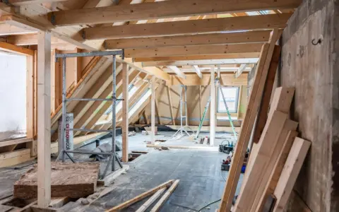 Aménagement d'un grenier : charpente en bois, fenêtres de toit, échafaudages et matériaux pour l'isolation comble aménageable.