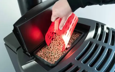 Main d'une personne versant des granulés de bois dans un poêle Palazzetti. Réglage de l'alimentation pour un fonctionnement optimal.