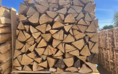 Un grand stère de bois, bien empilé et emballé sous plastique, prêt pour l'hiver.