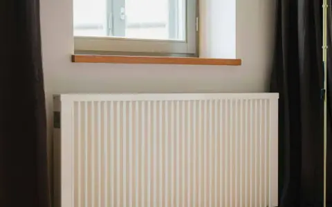 Radiateur électrique blanc sous une fenêtre, prêt pour un changement grâce à l'aide de l'état.