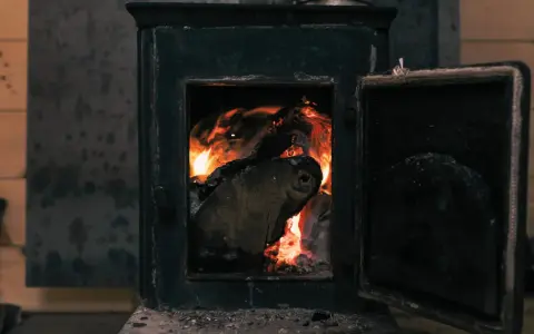 Poêle à bois avec porte ouverte et flammes vives dans le foyer.
