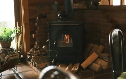 Poêle à bois avec arrivée d'air extérieur, crépitant joyeusement dans un coin cosy, entouré de bois prêt à chauffer.