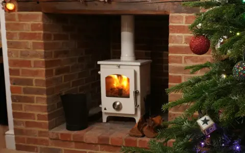 Installation d'un poêle à granulés avec conduit existant dans une cheminée en briques, décorée pour Noël.