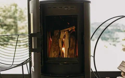 Poêle à bois allumé, avec une prise d'air poele à bois obligatoire pour une combustion optimale. Le feu crépite joyeusement.