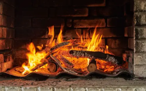 Un feu crépite dans une cheminée, réchauffant des morceaux de chêne bois de chauffage. Les flammes dansent joyeusement.