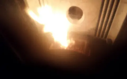 Flammes vives dans un poêle Piazzetta, peut-être un problème de tirage. La chaleur intense illumine l'intérieur.