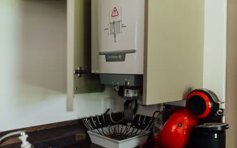 Chaudière gaz instantané De Dietrich installée dans un placard, à côté d'une machine à café rouge.