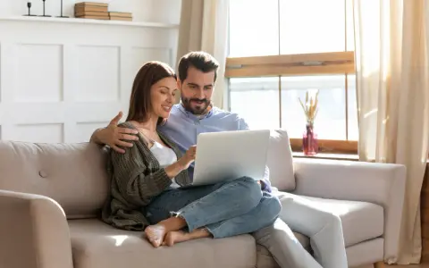 Couple planifiant l'amélioration de leur habitat, consultant un prêt sur leur ordinateur.