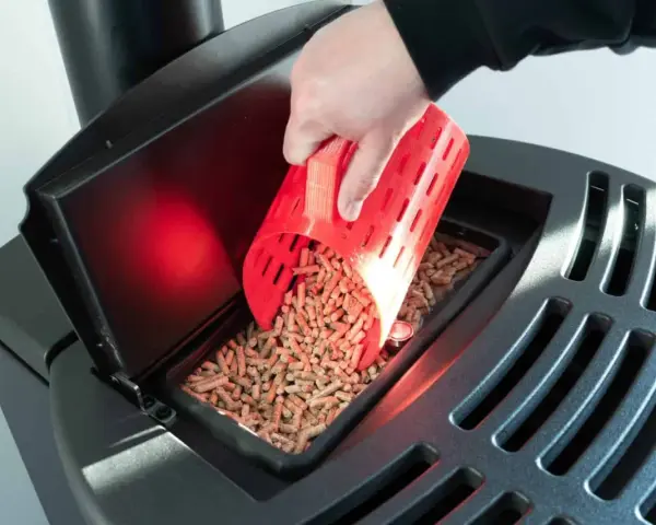 Main d'une personne versant des granulés de bois dans un poêle Palazzetti. Réglage de l'alimentation pour un fonctionnement optimal.