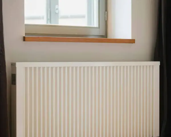 Radiateur électrique blanc sous une fenêtre, prêt pour un changement grâce à l'aide de l'état.