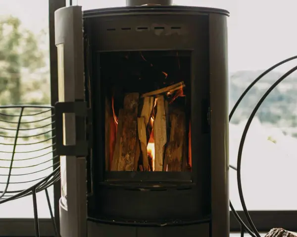 Poêle à bois allumé, avec une prise d'air poele à bois obligatoire pour une combustion optimale. Le feu crépite joyeusement.