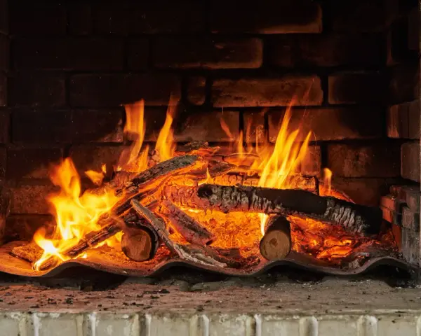 Un feu crépite dans une cheminée, réchauffant des morceaux de chêne bois de chauffage. Les flammes dansent joyeusement.