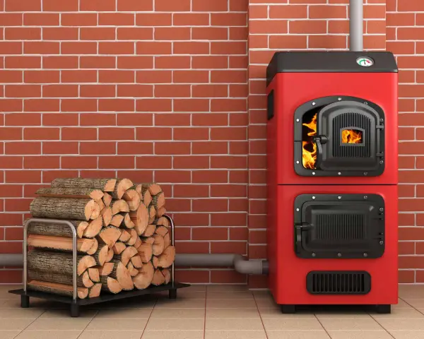 Une chaudière biomasse rouge flamboyante, avec une porte ouverte révélant des flammes vives, est prête à chauffer une maison. À côté, une pile de bois de chauffage attend patiemment.