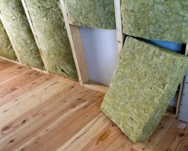Isolation d'un grenier avec de la laine de verre sans pare vapeur, posée entre les chevrons sur un plancher en bois.