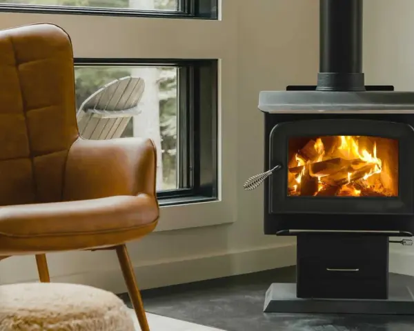 Un confortable fauteuil en cuir brun fait face à un poêle à bois non étanche, où des flammes dansent joyeusement dans le foyer.
