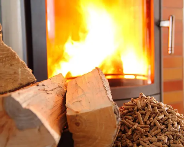 Bûches et granulés de bois près d'un poêle à granules en feu. Chaleur réconfortante pour l'hiver.