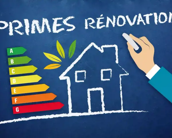 Une main dessine une maison sur un tableau bleu, avec une échelle d'efficacité énergétique et le texte "PRIMES RÉNOVATION".