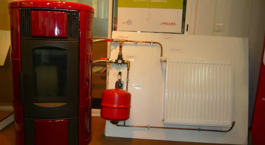 Poêle à granulé hydro rouge connecté à un radiateur blanc. Le système de chauffage est prêt.